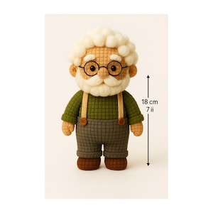 Może przedstawiać: Ręcznie robiona lalka starszego pana, o wysokości 18 cm, z białą brodą i włosami, w okrągłych okularach, zielonej koszuli, szarych spodniach i brązowych butach. Lalka ma szelki i detale guzików.