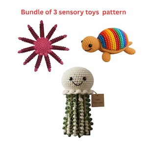 May include: A set of three crocheted sensory toys: a pink starfish, a turtle with a rainbow shell, and a jellyfish with green beaded tentacles. The jellyfish has a tag that says "Saira Exclusive".