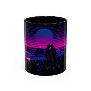 Puede incluir: Taza de cerámica negra con un diseño retro. El diseño incluye un coche azul, una pareja abrazándose y una vibrante puesta de sol con un gran orbe. La taza tiene un acabado brillante.