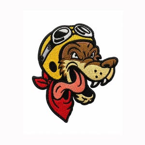 May include: An embroidered patch featuring a cartoon wolf wearing a yellow aviator helmet with white goggles. The wolf has brown fur, a long pink tongue hanging out, and a red bandana tied around its neck, all outlined in thick black thread.