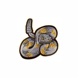 May include: A coiled rattlesnake patch featuring a gray and yellow scale pattern with a black border. The snake is depicted in a curled position with its rattle raised vertically, showcasing detailed eyes and a distinct head shape in a graphic style.
