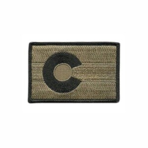 May include: A rectangular embroidered patch featuring a monochromatic tan and black colour scheme. The design displays the Colorado state flag emblem, consisting of a large black letter C surrounding a tan circle, set against a tan background.