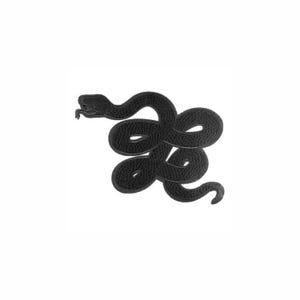 Puede incluir: Un parche bordado negro con la forma de una serpiente enroscada. El diseño presenta una superficie texturizada con patrones de costura visibles que definen el cuerpo de la serpiente mientras se curva en una forma compacta y entrelazada.