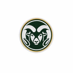 May include: A circular embroidered patch featuring a stylised white ram head with large curved horns centred on a dark green background. The design is enclosed by a thin gold circular border and a white outer edge, creating a clean graphic emblem.