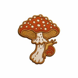 Könnte beinhalten: Ein gestickter Aufnäher mit einem rostorangen Pilz, der weiße Punkte auf dem Hut und einen cremefarbenen Stiel hat. Eine kleine, goldbraune Schnecke mit einem spiralförmigen Gehäuse befindet sich am Pilzstiel, alles mit braunem Garn umrandet.