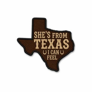 Könnte beinhalten: Ein brauner bestickter Aufnäher in Form des Bundesstaates Texas mit schwarzem Rand. Der Text lautet SHE'S FROM TEXAS I CAN FEEL in beigefarbener Schrift, mit zwei kleinen beigen Hufeisensymbolen neben den Wörtern I CAN in der dritten Zeile.