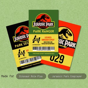 Może przedstawiać: Trzy prostokątne identyfikatory z logo Jurassic Park. Czarny identyfikator z napisem Park Security, zielony z napisem Park Ranger oraz czerwony z numerem 029. Każdy z nich zawiera oznaczenia InGen oraz kody kreskowe.