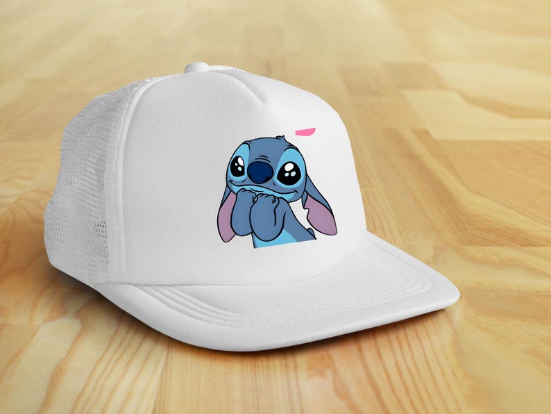 May include: White trucker hat featuring a cartoon image of Stitch from Lilo & Stitch. The character is blue with large eyes and pink ears. The hat has a mesh back and a curved brim.