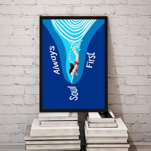 Può includere: Stampa artistica incorniciata con una subacquea in costume da bagno rosso che scende in acqua blu. L'opera d'arte include le parole "Always Soul First" in testo bianco. La stampa è esposta su una pila di libri contro un muro di mattoni bianchi.