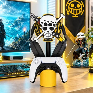 May include: A black and yellow gaming stand featuring a white skull and crossbones emblem with a sword and bone design. The stand holds a pair of black over-ear headphones on the top section and a white and black wireless game controller below.