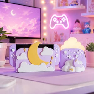 May include: A lavender gaming console dock featuring a large yellow crescent moon and white clouds, accompanied by a matching lavender wireless controller stand decorated with a smaller moon and cloud motif, both with small yellow star accents.