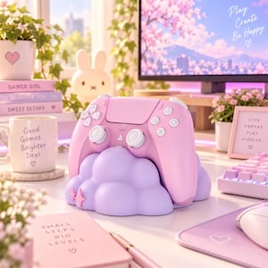 Puede incluir: Un mando de juego inalámbrico rosa pastel descansa sobre un soporte con forma de nube de color violeta claro. El mando cuenta con joysticks y botones blancos. El soporte tiene una superficie lisa y redondeada con pequeñas estrellas al frente.