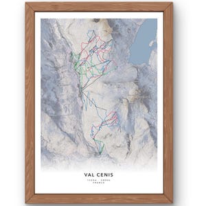 May include: A detailed map of the Val Cenis ski resort in France, showing the ski runs and lifts. The map is printed on white paper and framed in a light brown wood frame. The map shows the elevation range of the resort, 1300m - 2800m.