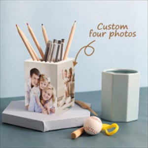 Puede incluir: Un portalápices personalizado con cuatro fotos personalizadas. El portalápices contiene lápices y bolígrafos. También hay una pelota de béisbol, un bate y un pequeño recipiente de cerámica verde claro. El texto "Custom four photos" es visible.