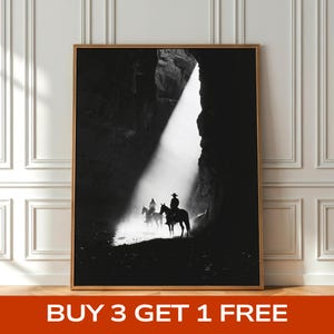 Könnte beinhalten: Schwarz-Weiß-Druck mit Rahmen, der drei Cowboys auf Pferden zeigt, die vor hellem Licht in einer dunklen Schlucht silhouettiert sind. Der Druck ist in einem Holzrahmen. Der Text "BUY 3 GET 1 FREE" befindet sich unten im Bild.