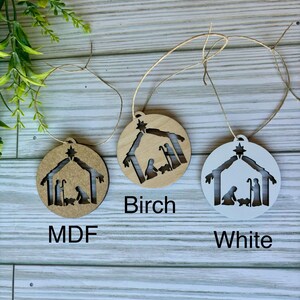 May include: Three wooden ornaments with a nativity scene cutout. The ornaments are in three different finishes: MDF, birch, and white.