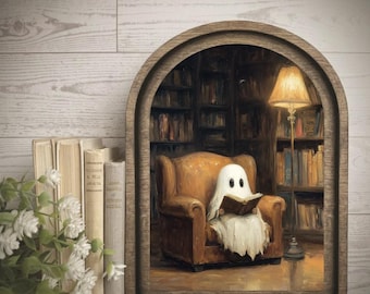 May include: A framed wall art piece featuring a white ghost sitting in a brown armchair reading a book inside a library. A tall floor lamp stands beside the chair. To the left of the frame, a small bouquet of white flowers sits near three books.