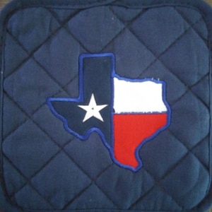 May include: Blue quilted pot holder with a white and red embroidered Texas state outline.