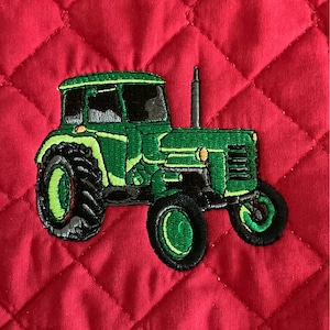May include: Green tractor embroidered on a red quilted fabric pot holder.