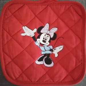 May include: Red quilted pot holder with an embroidered image of Minnie Mouse in a blue dress and a pink bow.
