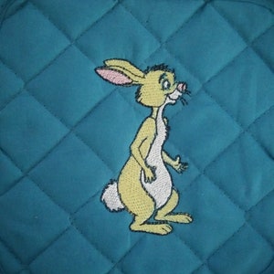 May include: Teal quilted pot holder with a yellow embroidered rabbit with white accents.