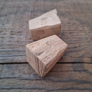 Può includere: Due blocchi di legno, uno è un prisma triangolare e l'altro è un prisma rettangolare. Entrambi i blocchi sono in legno marrone chiaro.