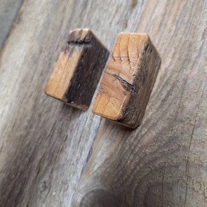 Könnte beinhalten: Zwei kleine Holzblöcke mit rustikalem, verwittertem Finish. Die Blöcke sind rechteckig und haben ein natürliches Holzmaserungsmuster.