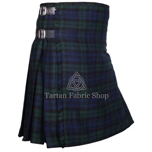May include: A traditional kilt in a green and blue plaid pattern. The kilt features leather straps with silver buckles and fringe detailing. The text "Tartan Fabric Shop" is visible on the kilt.