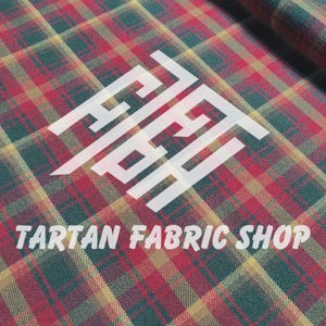 Op de afbeelding: Tartan stof met een rood, groen en geel ruitpatroon. De stof heeft een diagonale weefsel en de tekst "TARTAN FABRIC SHOP" wordt in het wit weergegeven.