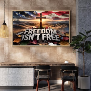 Könnte beinhalten: Ein gerahmter Druck mit patriotischem Thema. Das Bild zeigt eine amerikanische Flagge mit einem Holzkreuz davor. Der Text "FREEDOM ISN'T FREE" ist in großen Buchstaben auf dem Boden vor dem Kreuz geschrieben.