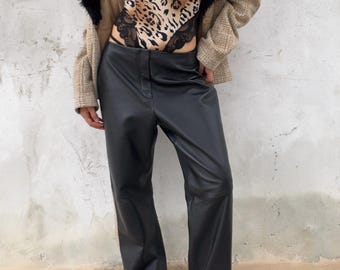 Könnte beinhalten: Eine beige karierte Jacke mit schwarzem Kunstfellkragen über einem Body mit Leopardenmuster und schwarzer Spitzenborte, kombiniert mit einer schwarzen Hose und transparenten Plateausandalen mit silbernen Absätzen.