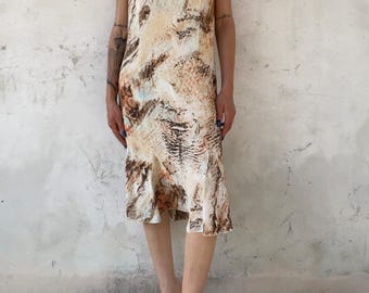 Könnte beinhalten: Ein knielanges Kleid mit V-Ausschnitt und kurzen, flatternden Ärmeln. Das Kleidungsstück ist mit einem abstrakten, mehrfarbigen Druck in Beige-, Creme- und Dunkelbrauntönen verziert, der ein strukturiertes, marmoriertes Erscheinungsbild erzeugt.