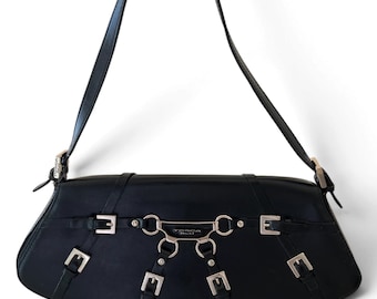Könnte beinhalten: Eine schwarze Schultertasche mit geschwungener Silhouette, einem einzelnen Riemen und silberfarbenen Beschlägen. Die Vorderseite ist mit sechs kleinen Schnallen und einer Metallplatte mit der Aufschrift Tosca Blu verziert.