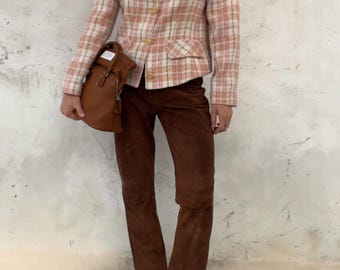 Könnte beinhalten: Ein rosafarbenes und weißes kariertes Sakko mit goldenen Knöpfen, kombiniert mit einer dunkelbraunen Wildlederhose und einer braunen Ledertasche. Das Outfit wird durch transparente Sandaletten mit Absatz ergänzt, was einen strukturierten Look ergibt.
