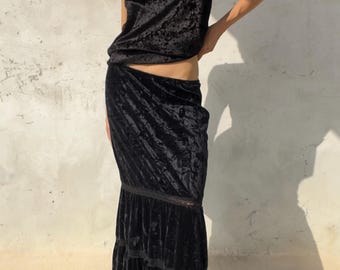Könnte beinhalten: Ein schwarzes Camisole-Top aus zerknittertem Samt mit Spitzenbesatz am Ausschnitt, kombiniert mit einem passenden bodenlangen Rock aus zerknittertem Samt mit gestuften Rüschen und feinen Spitzendetails an den Nähten.