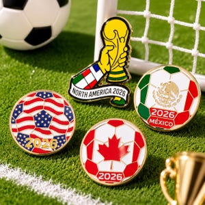 May include: Four metal enamel pins featuring soccer themes. One pin shows a gold trophy with the text NORTH AMERICA 2026. Three circular pins depict soccer balls with the flags of the USA, Mexico with the text 2026 MÉXICO, and Canada with 2026.