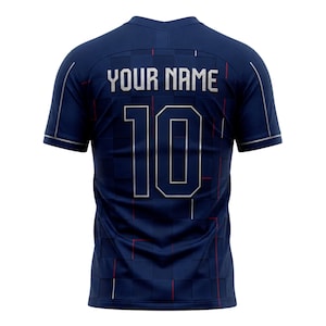 May include: Navy blue athletic jersey with the text "YOUR NAME" and the number "10" in silver. The jersey has a grid pattern with red accents. The sleeves and collar are trimmed in silver.