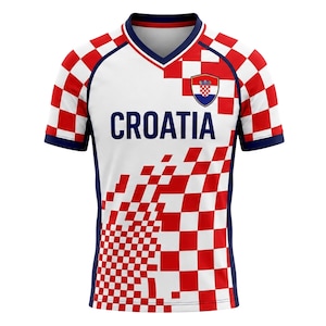 May include: A white and red checkered Croatia soccer jersey with the word "CROATIA" in navy blue. The jersey has a navy blue V-neck collar and sleeves. A Croatian coat of arms is on the upper chest.