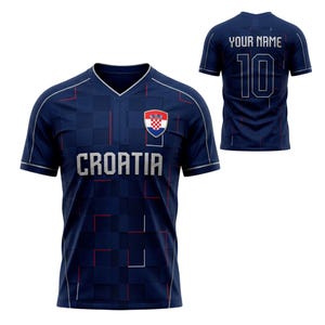 May include: A navy blue soccer jersey with the word "CROATIA" in silver letters. The jersey has a checkered pattern and a Croatian flag emblem. The back of the jersey displays the number 10 and the text "YOUR NAME" in silver.