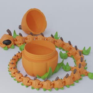 Könnte beinhalten: Ein orangefarbener, kürbisförmiger Behälter mit Deckel, umgeben von einem segmentierten, raupenartigen Design. Die Raupe hat kürbisförmige Segmente, grüne Blattakzente und braune Stieldetails. Der Behälter ist geöffnet.