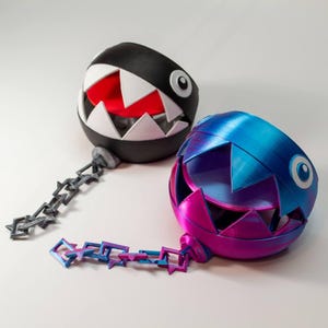 May include: Two 3D printed Chain Chomp figures. One is black with a red mouth and the other is blue and purple with a pink mouth.