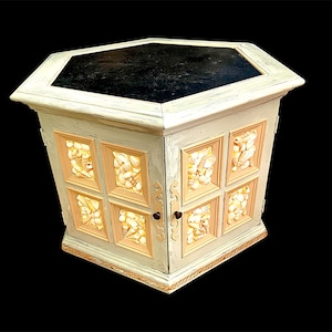May include: A white hexagonal table with a black top and a door with a shell design. The door is open and the inside is lit with warm light.