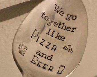 May include: A silver spoon with the text "We go together like pizza and beer" engraved on it. The spoon has a small pizza slice and beer mug icon.