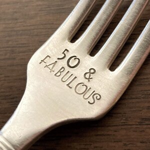 May include: Silver fork with the words "50 & Fabulous" engraved on the handle.