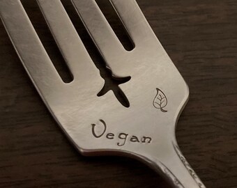 May include: A silver fork with a leaf design and the word "Vegan" engraved on the handle.