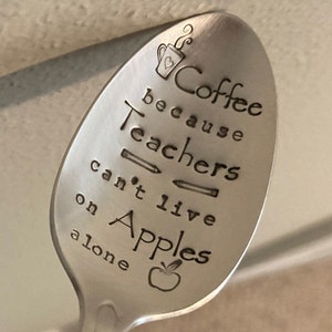 May include: A silver spoon with the text "Coffee because teachers can't live on apples alone" engraved on it. The spoon has a coffee cup, pencils, and an apple engraved on it.
