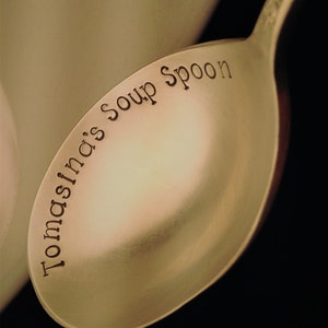 May include: A gold-colored soup spoon with the words "Tomasina's Soup Spoon" engraved on the bowl.