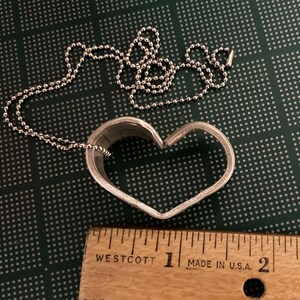 May include: A silver heart-shaped pendant necklace with a ball chain. The pendant is about 1 inch in diameter.