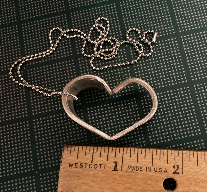 May include: A silver heart-shaped pendant necklace with a ball chain. The pendant is about 1 inch in diameter.
