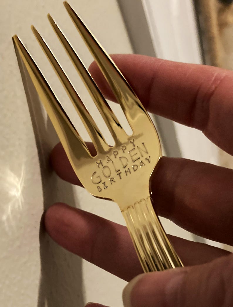 May include: A gold-colored fork with the words "Happy Golden Birthday" engraved on the handle.
